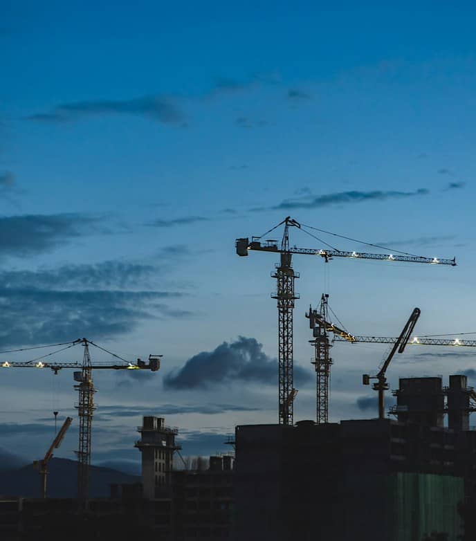 Gruas de construção num estaleiro de obras ao entardecer