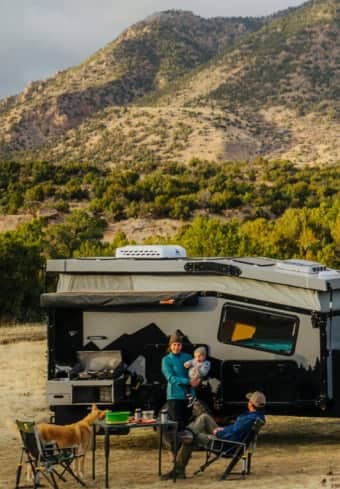 Família relaxando ao lado do seu motorhome nas montanhas